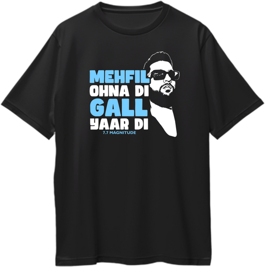 Black oversized Karan Aujla t-shirt with Mehfil Ohna Di Gall Yaar Di 7.7 Magnitude text and illustrated face graphic in white and sky blue – Garrari fan merch.