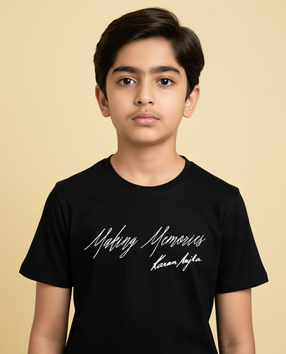 Kid wearing black “Making Memories” Karan Aujla kids unisex T-shirt with signature-style print